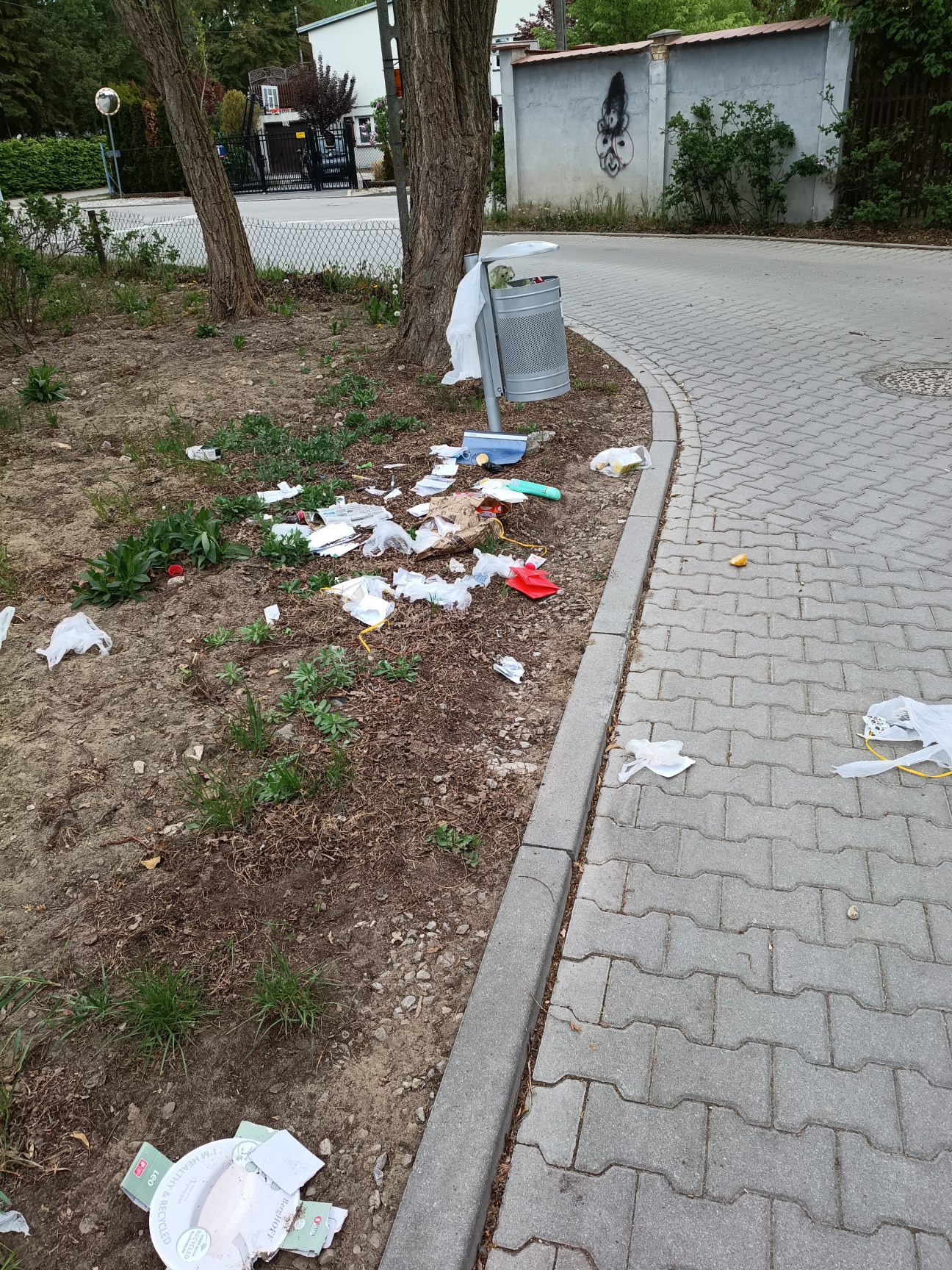 Zdjęcie rozsypanych śmieci z kosza przy ulicy
